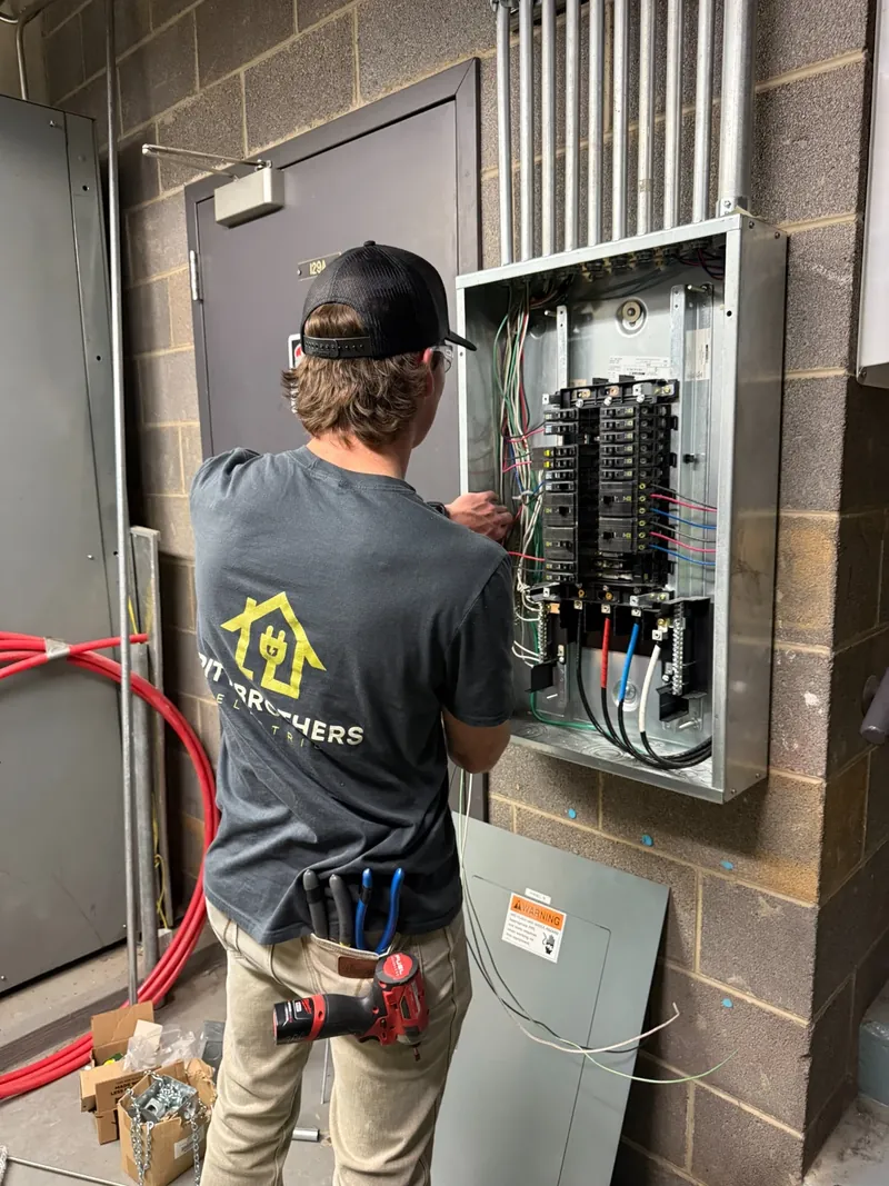 Hunter working on an electrical panel in his Pitt Brothers Electric shirt.
